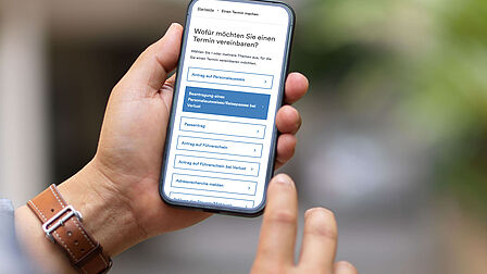 Person hält ein Smartphone, auf dem eine Website geöffnet ist. 